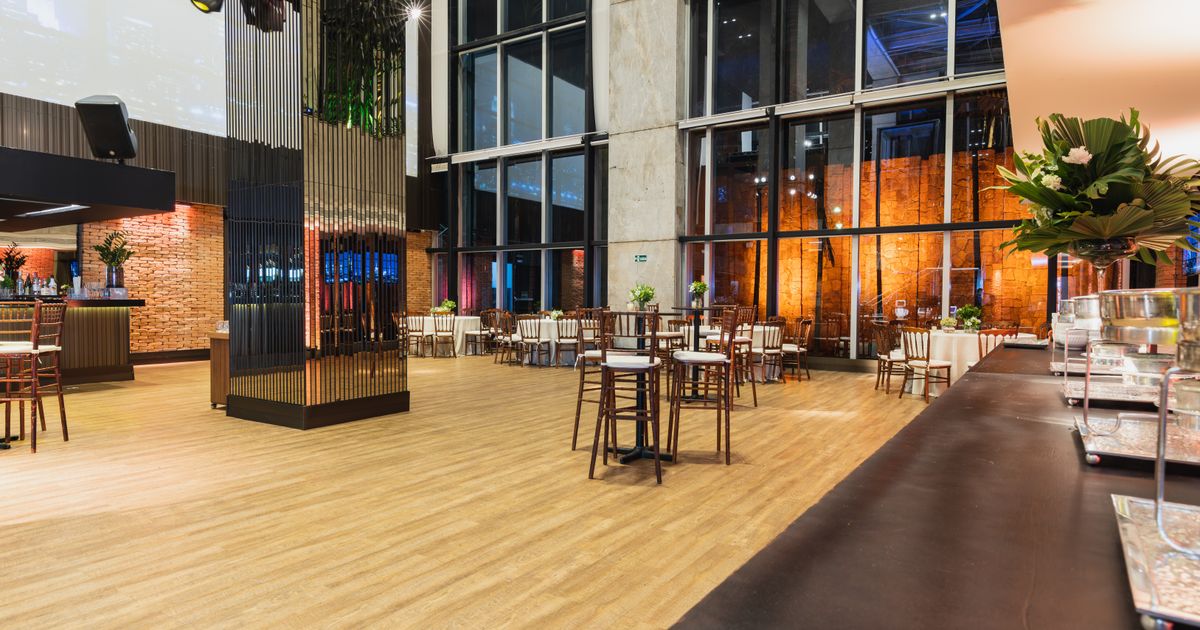 An event hall shown wide, its floor, tables and tall windows all in view