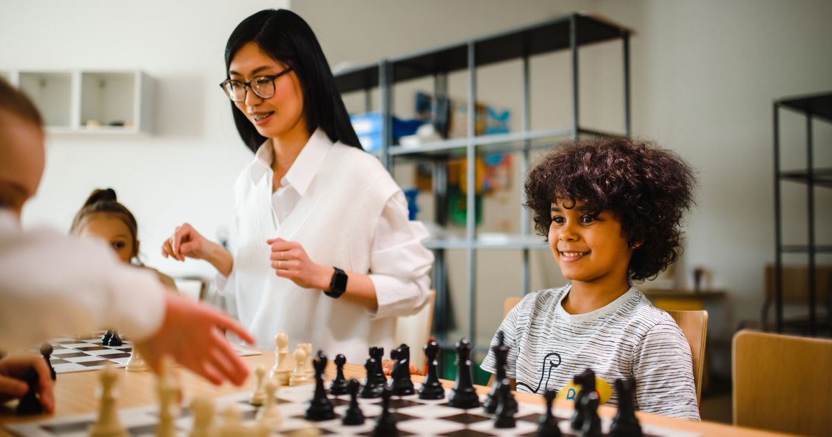 A teacher with children around a chess board at an after-school program