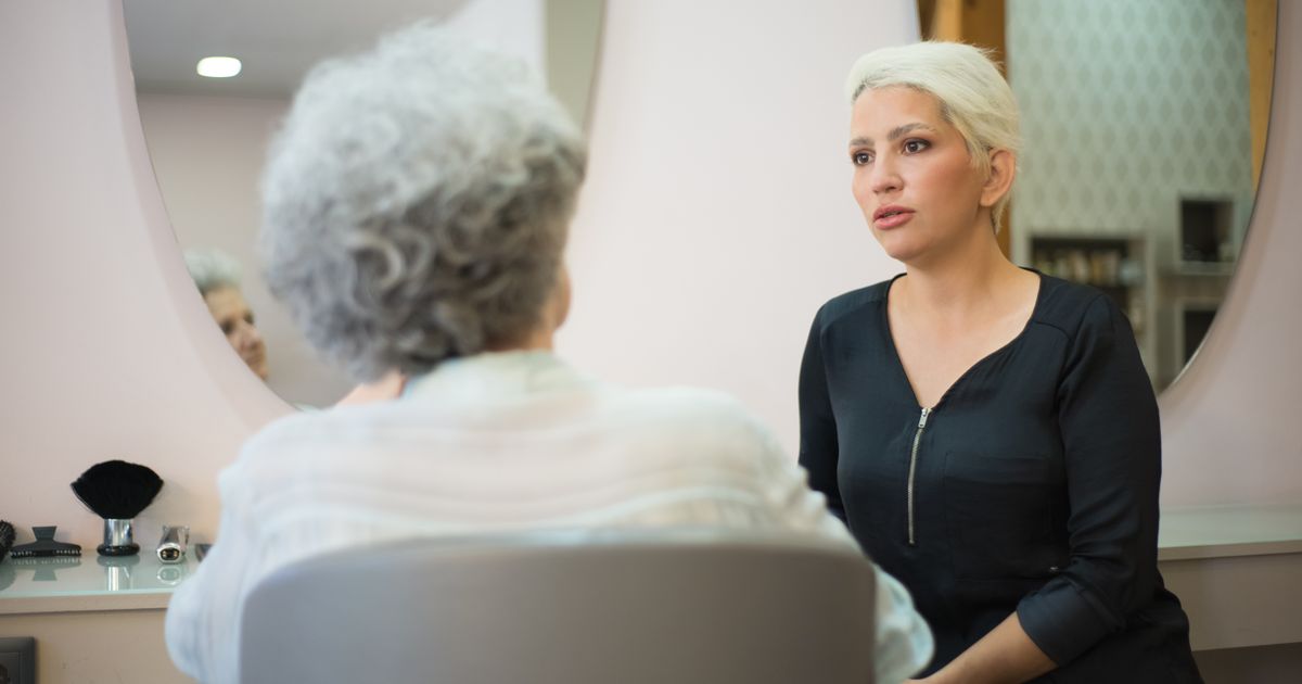 A stylist and a client talking it through in front of the salon mirror