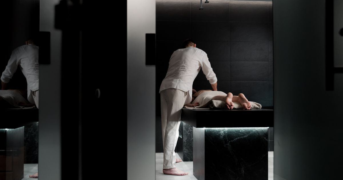 A therapist giving a back massage in a dim spa treatment room