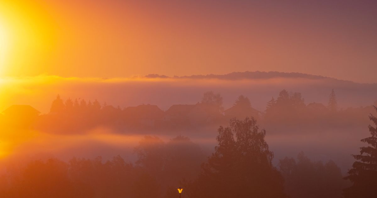 The sun rising over a town still in morning fog