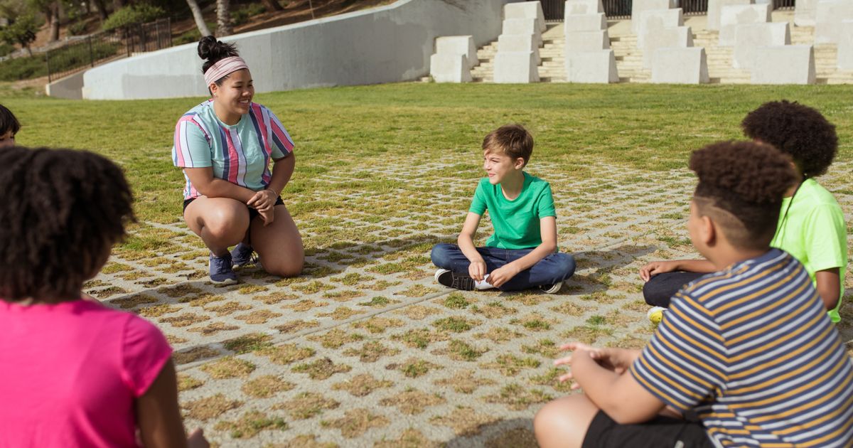 Children sitting in a circle outdoors for a morning activity at day camp