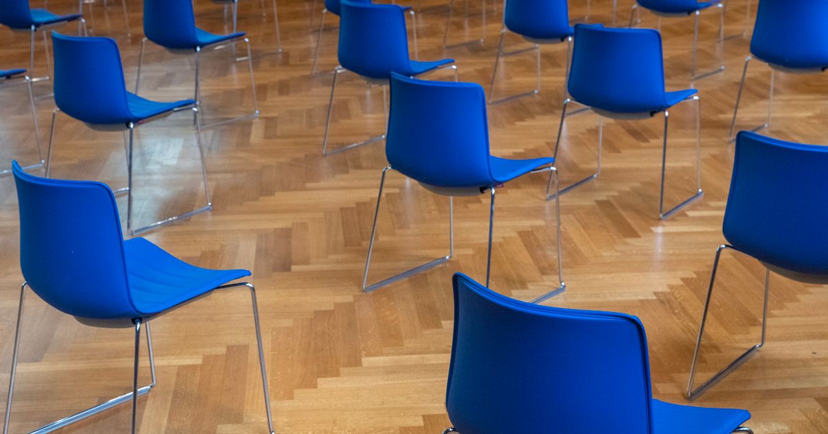Rows of empty blue chairs on a wooden floor, a seat for every student