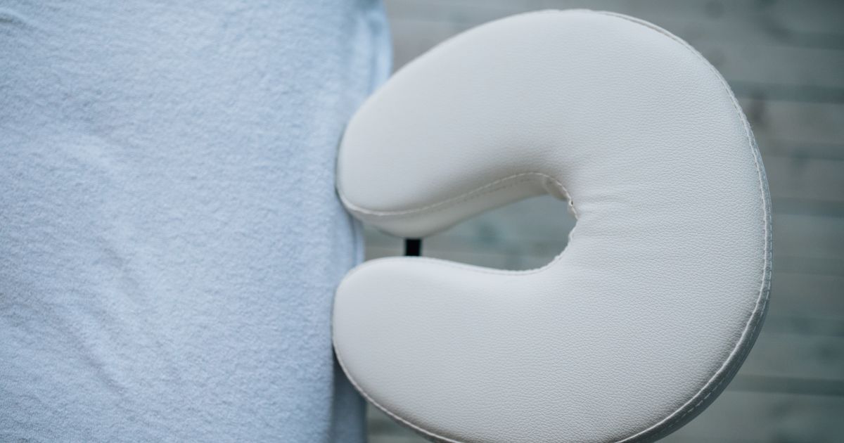 A massage table's white face rest beside its towel, close up