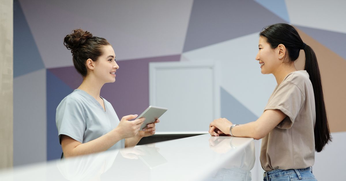 A receptionist talking with a visitor across the front desk