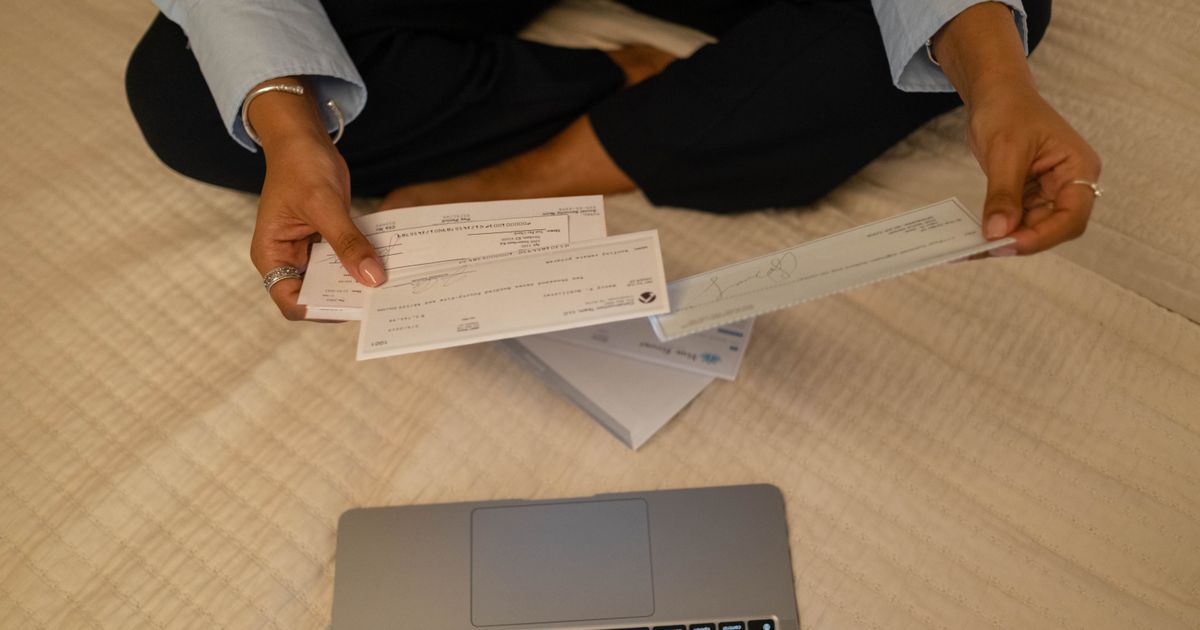 A volunteer treasurer sorting the season's cheques beside a laptop