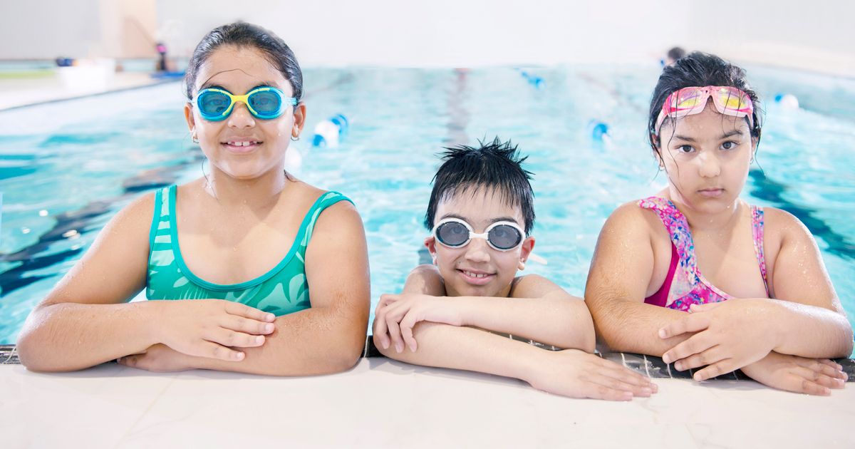 Three smiling children in a warm indoor pool