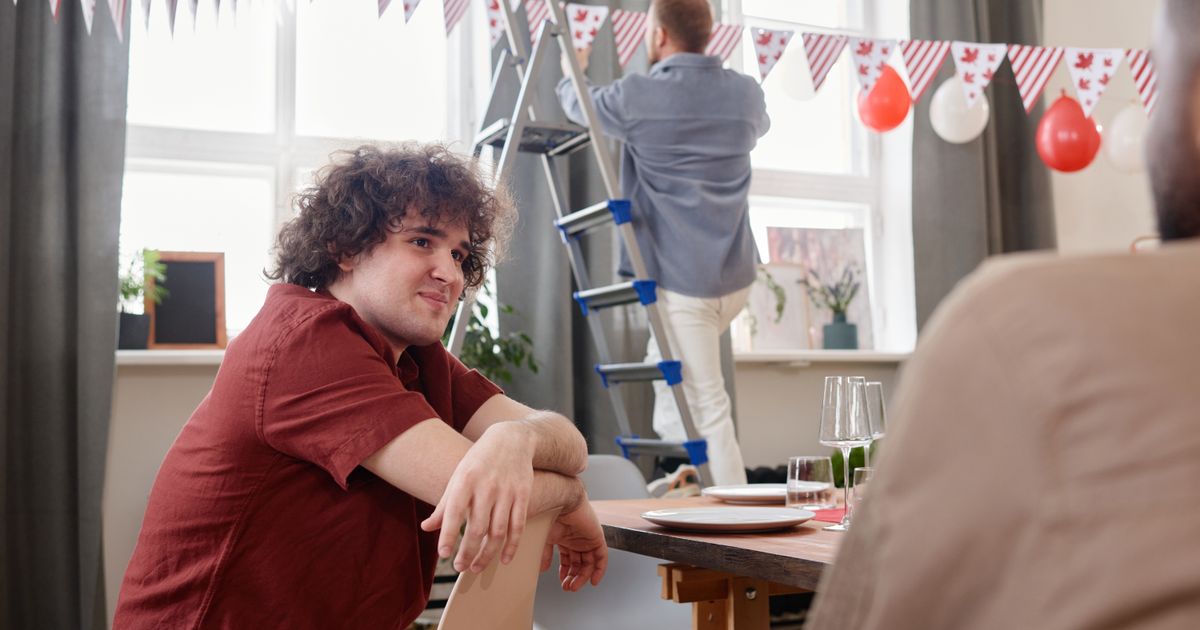 Someone on a ladder hanging bunting while the tables are set for a party