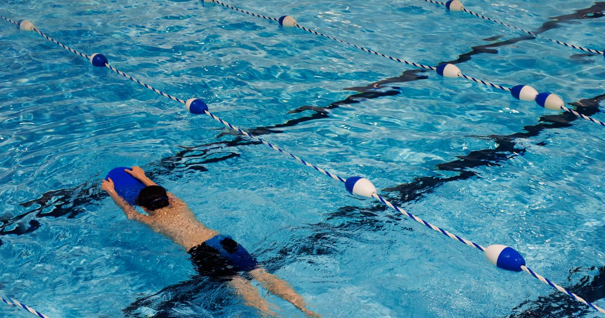 A young swimmer kicking across the pool with a kickboard