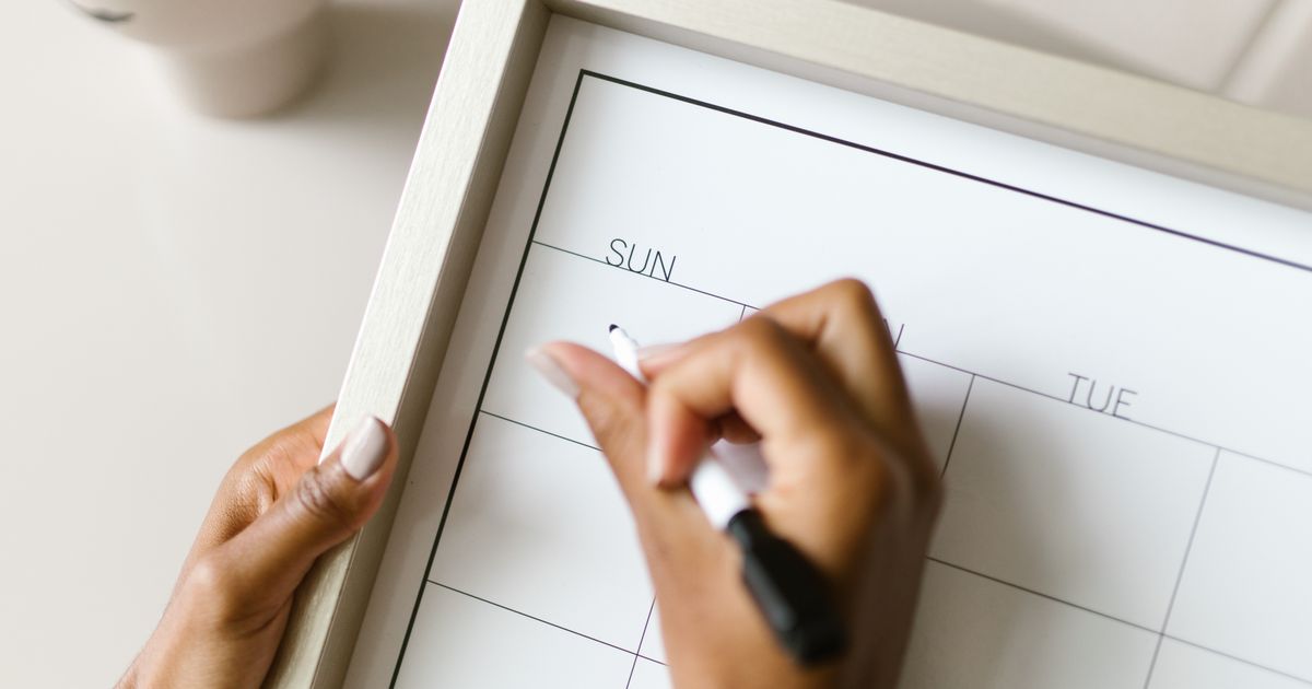 Hands holding a wall calendar and changing a week with a marker