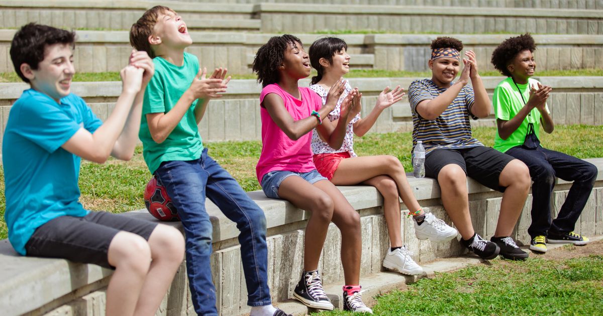 Campers sitting together outdoors, clapping and cheering on the last day