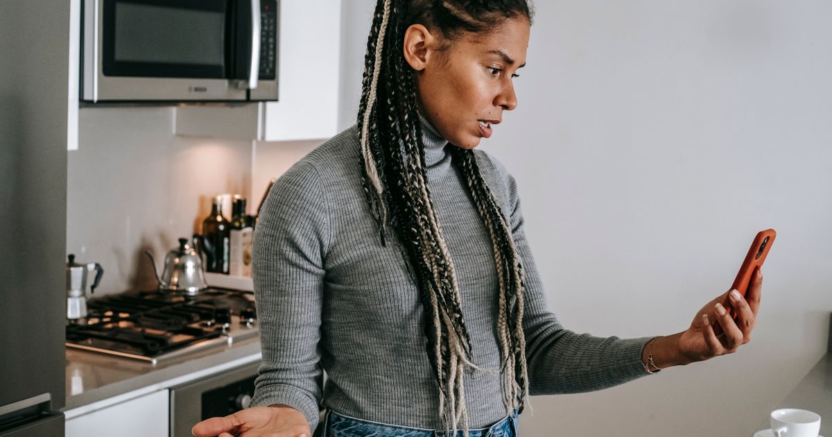 A parent in the kitchen, puzzled by a form on their phone