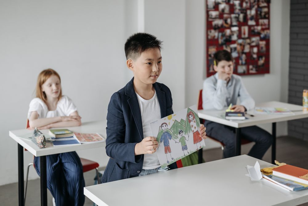 A boy showing his drawing to the class