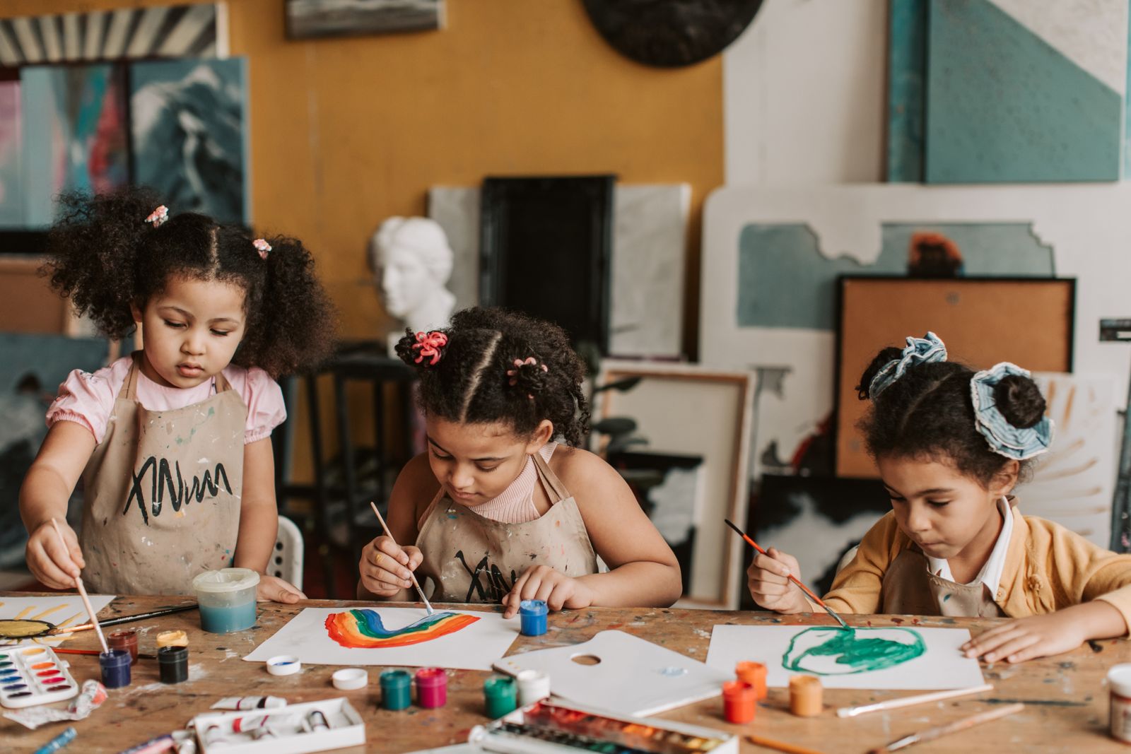 Children painting at a shared table in an art studio