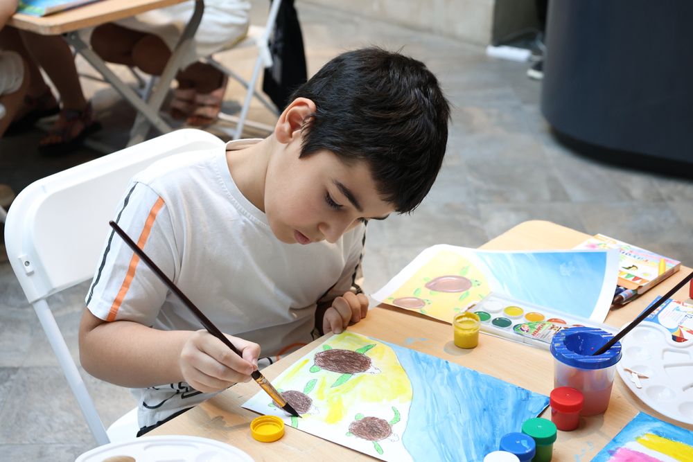 A boy painting sunflowers in watercolour