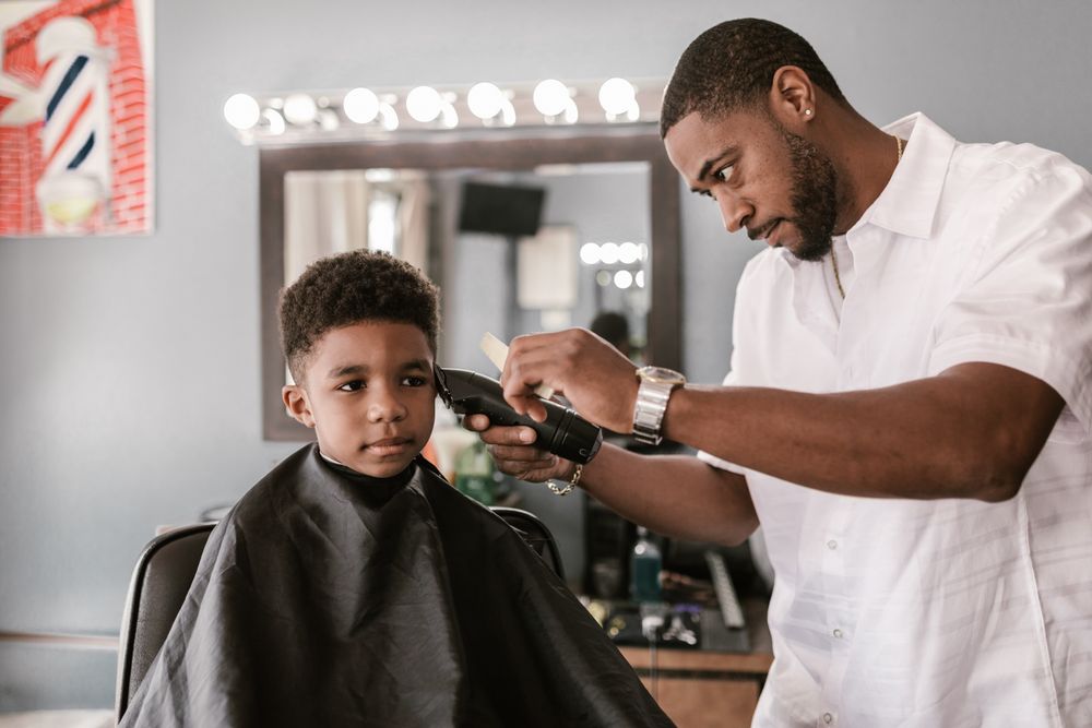 A barber taking the clippers to a boy's hair