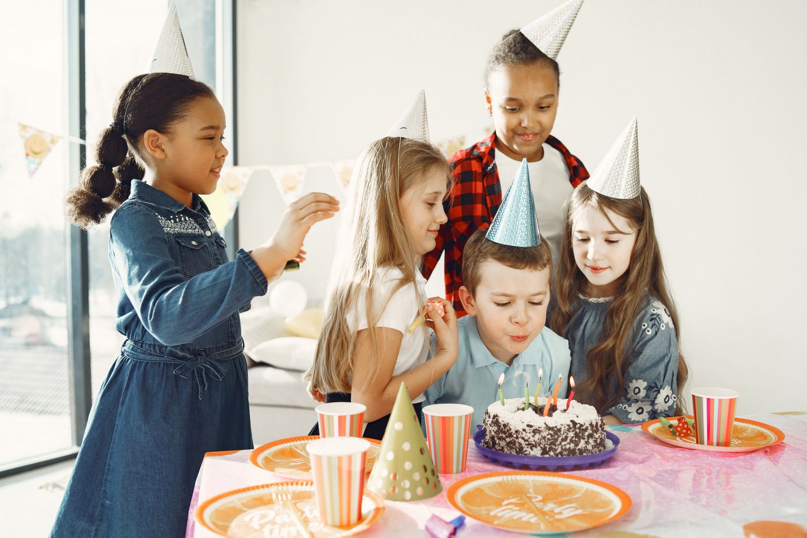 Children around the cake table blowing out candles