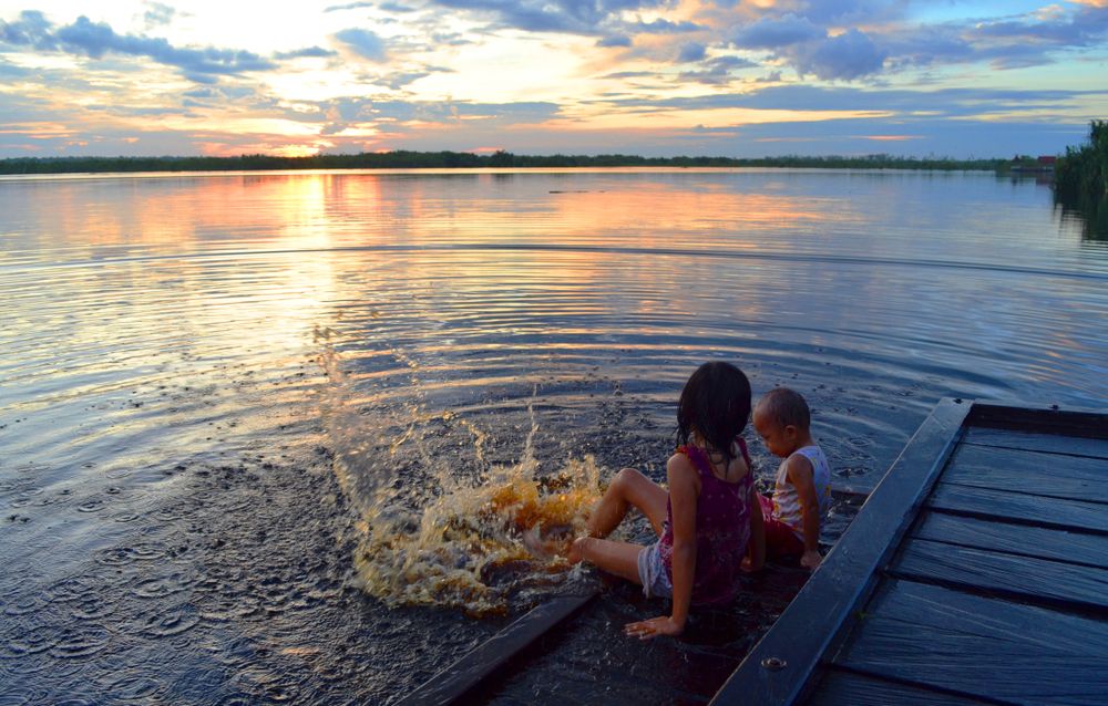 Children splashing off a dock at sunset