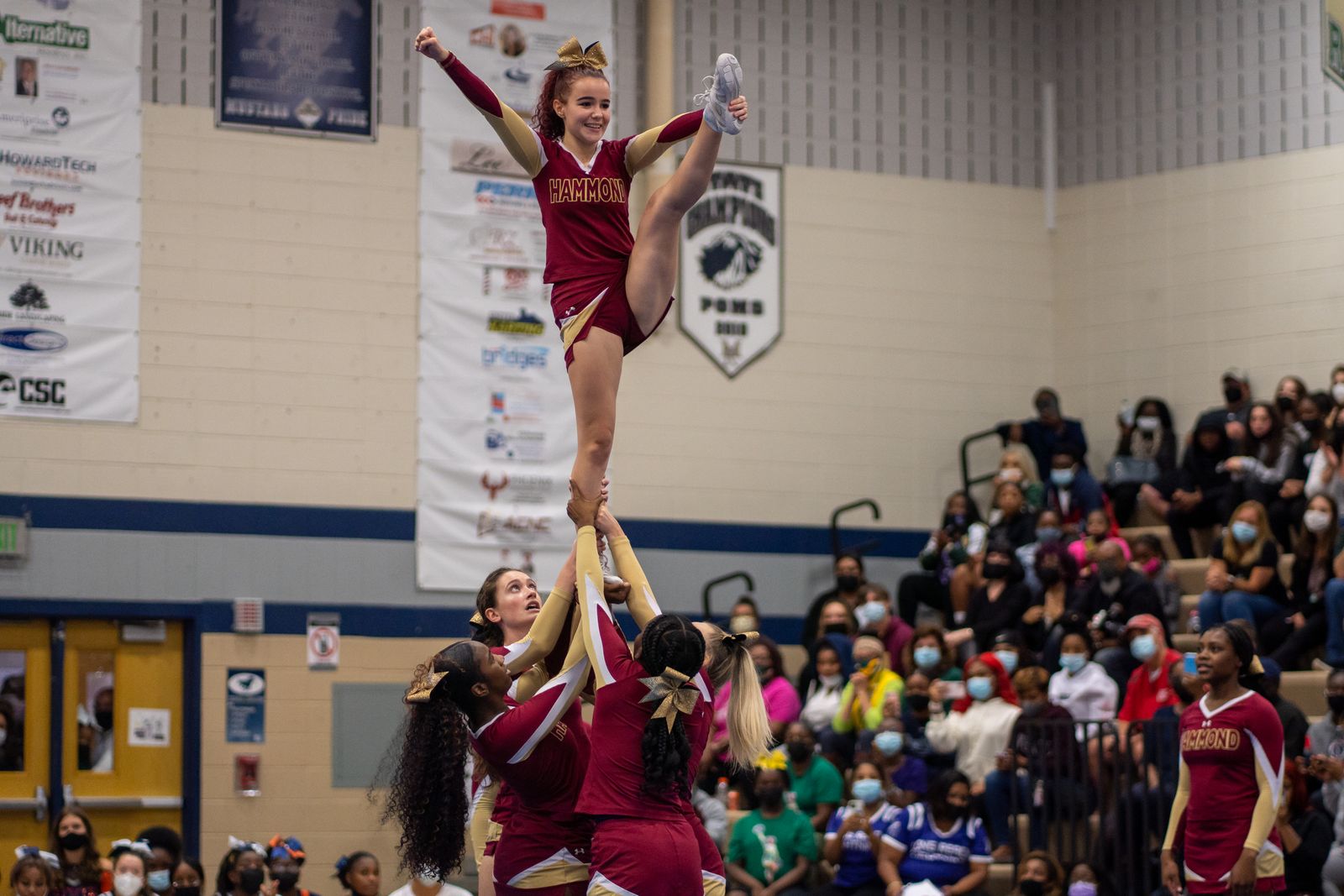 A cheer team holding a stunt in front of a crowd
