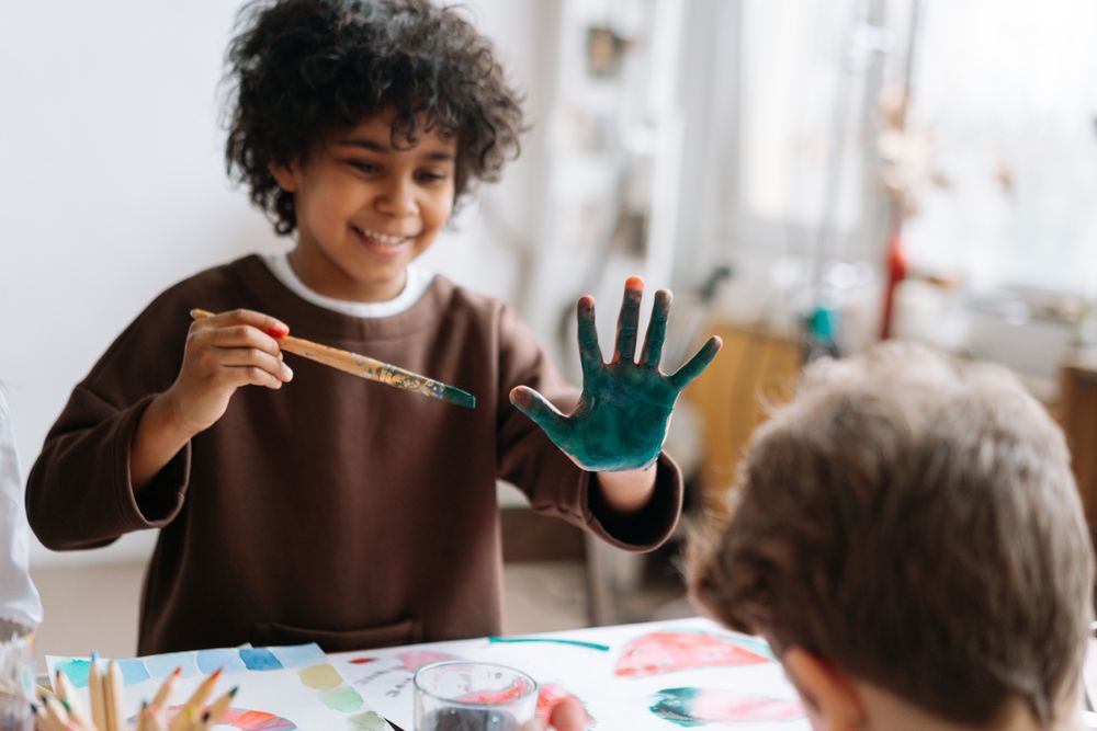 A boy with painted hands in an art class