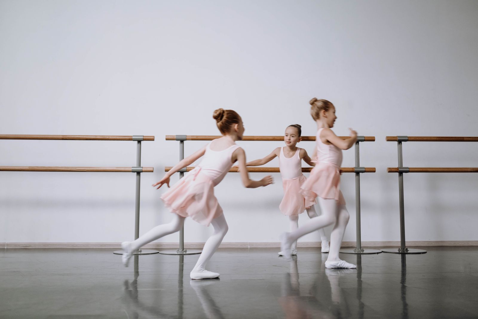 Young ballet students mid-leap across a bright studio