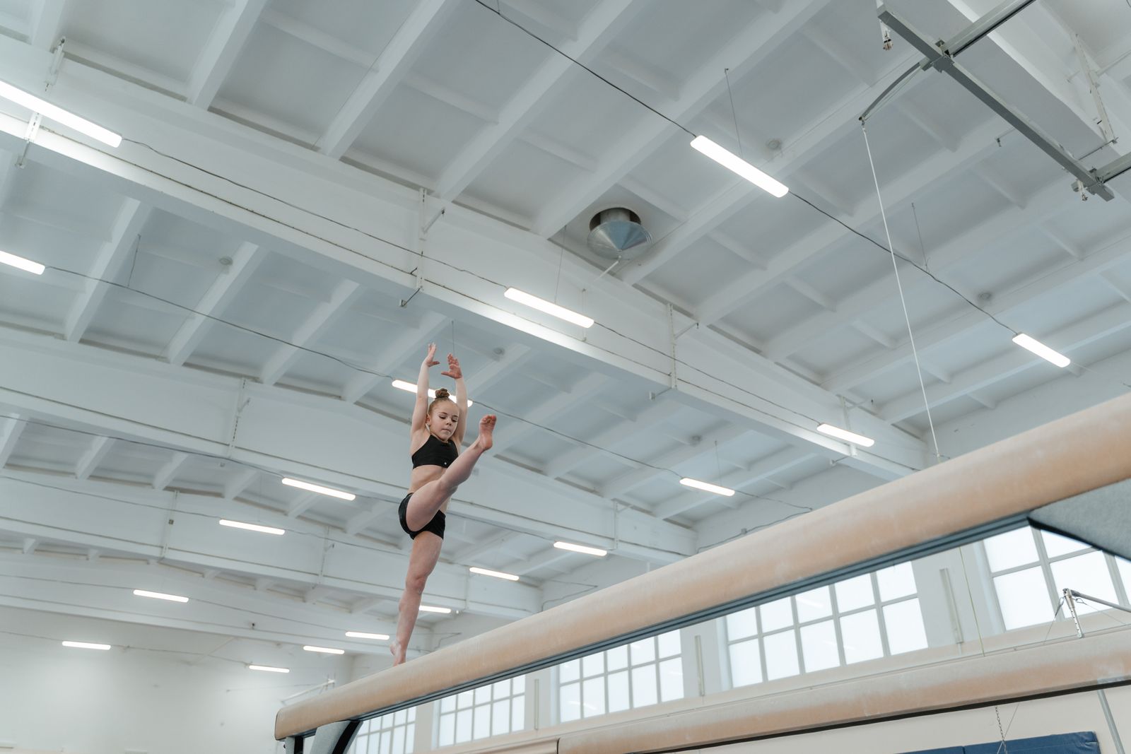 A young gymnast mid-routine on the balance beam