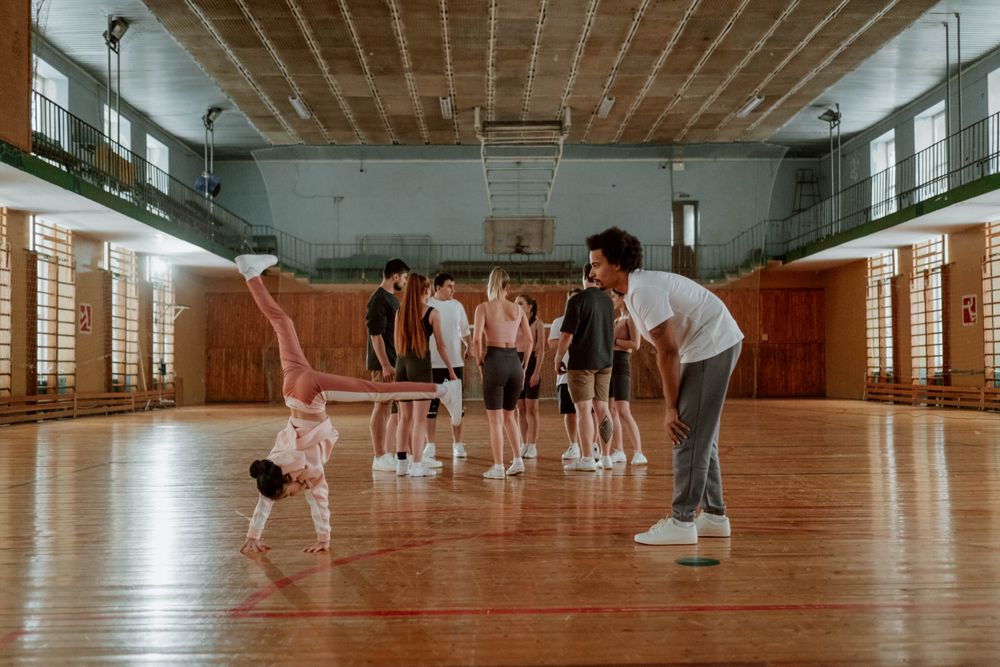 A coach watching a cartwheel in a busy gym