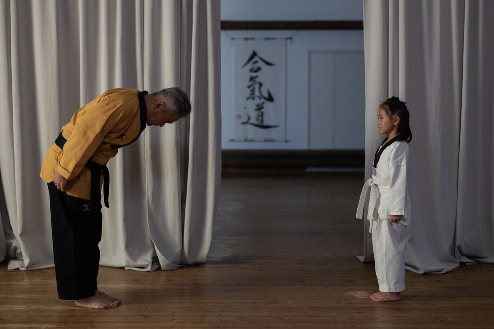 An instructor and a young student bowing on the mat
