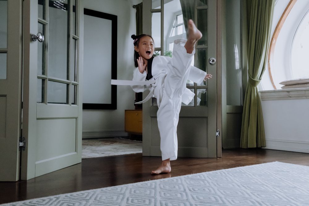 A girl mid-kick in her dobok