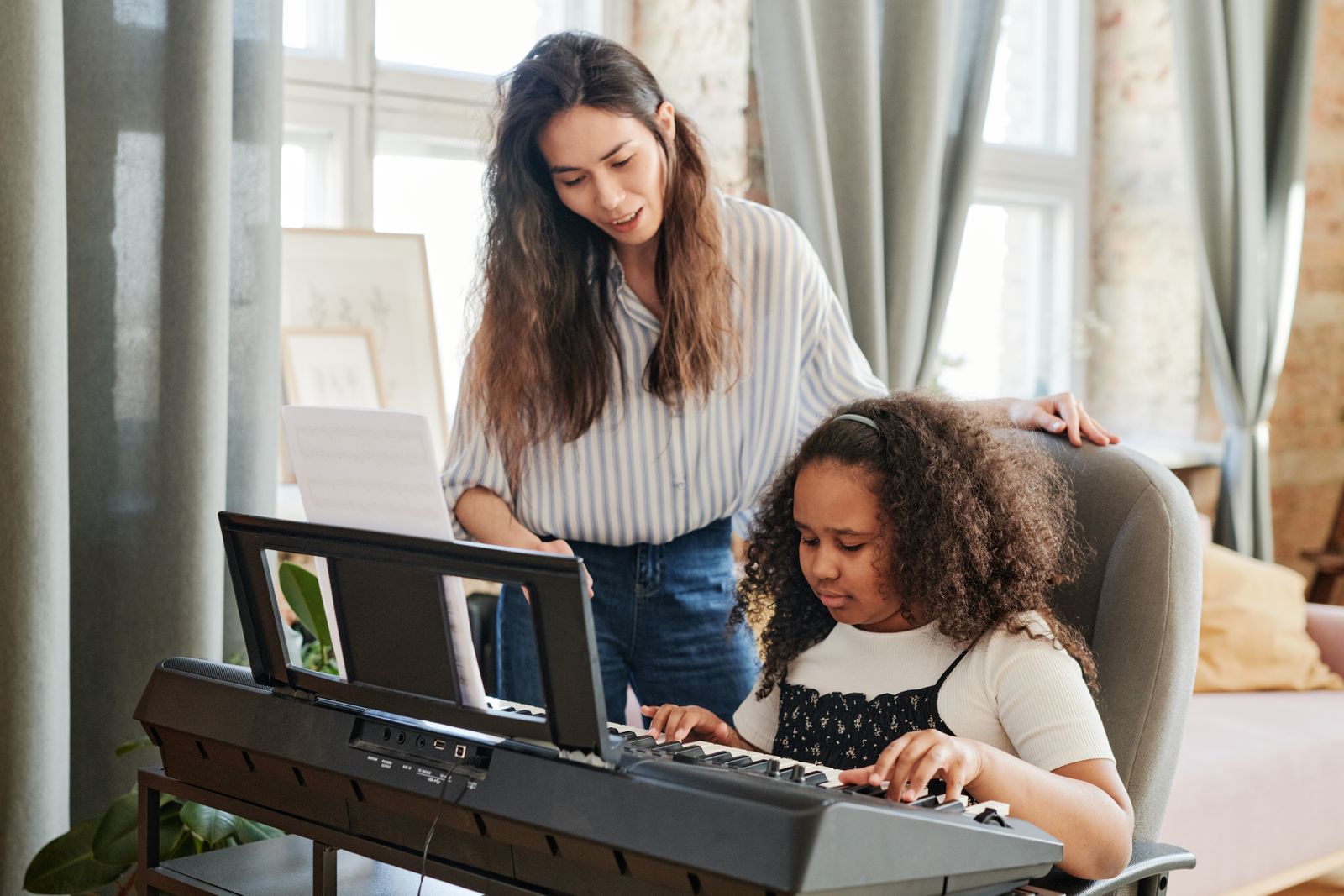 A teacher beside a student at the piano