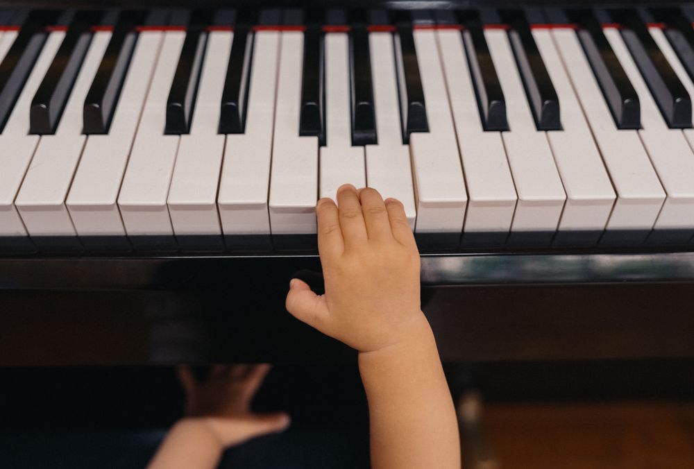 A small hand reaching for the piano keys