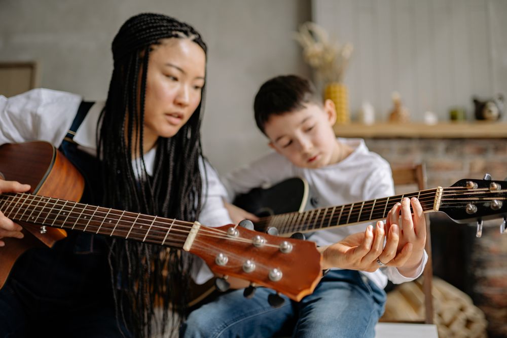 A guitar lesson, teacher and student side by side