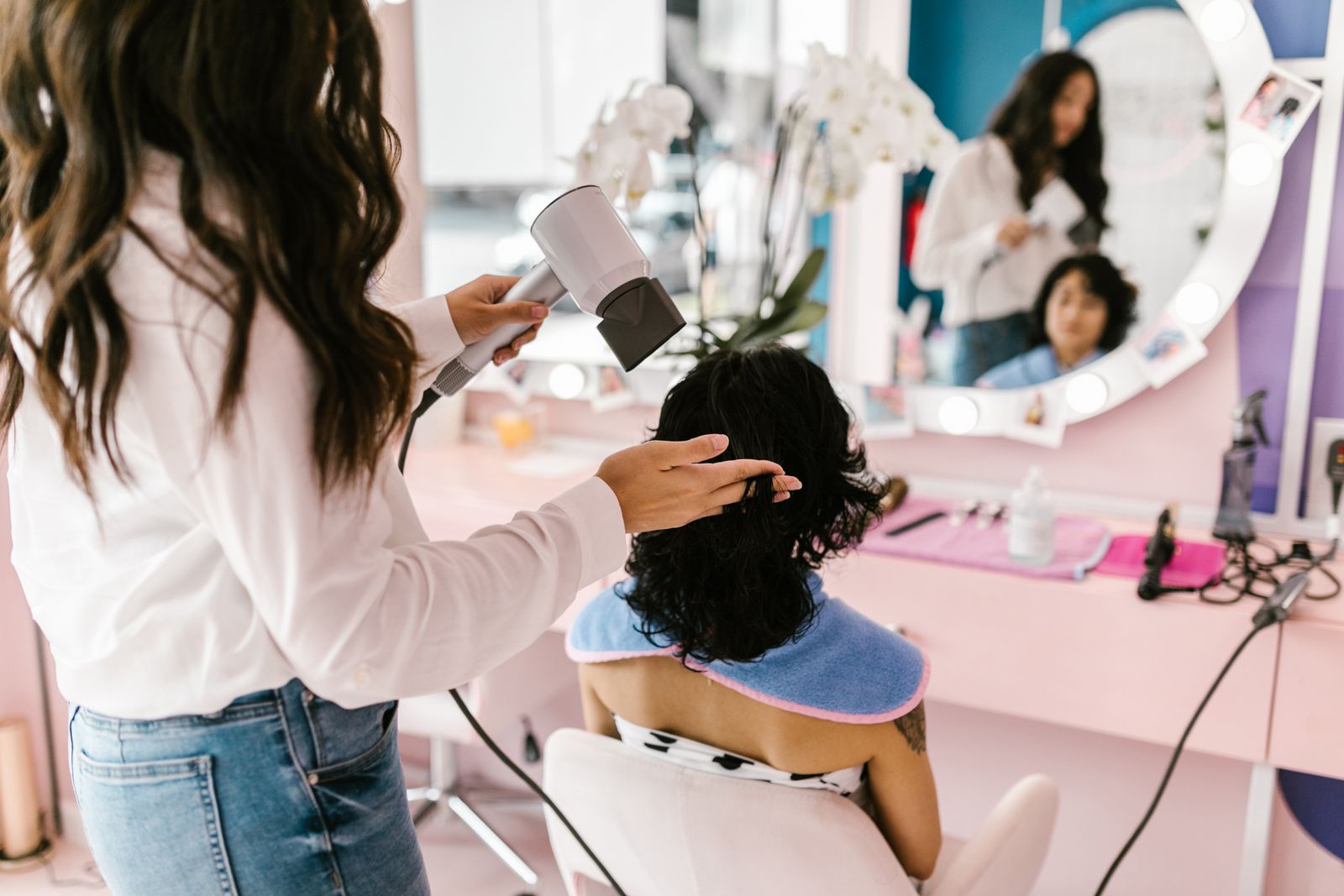 A stylist blow-drying a client's hair in a bright salon