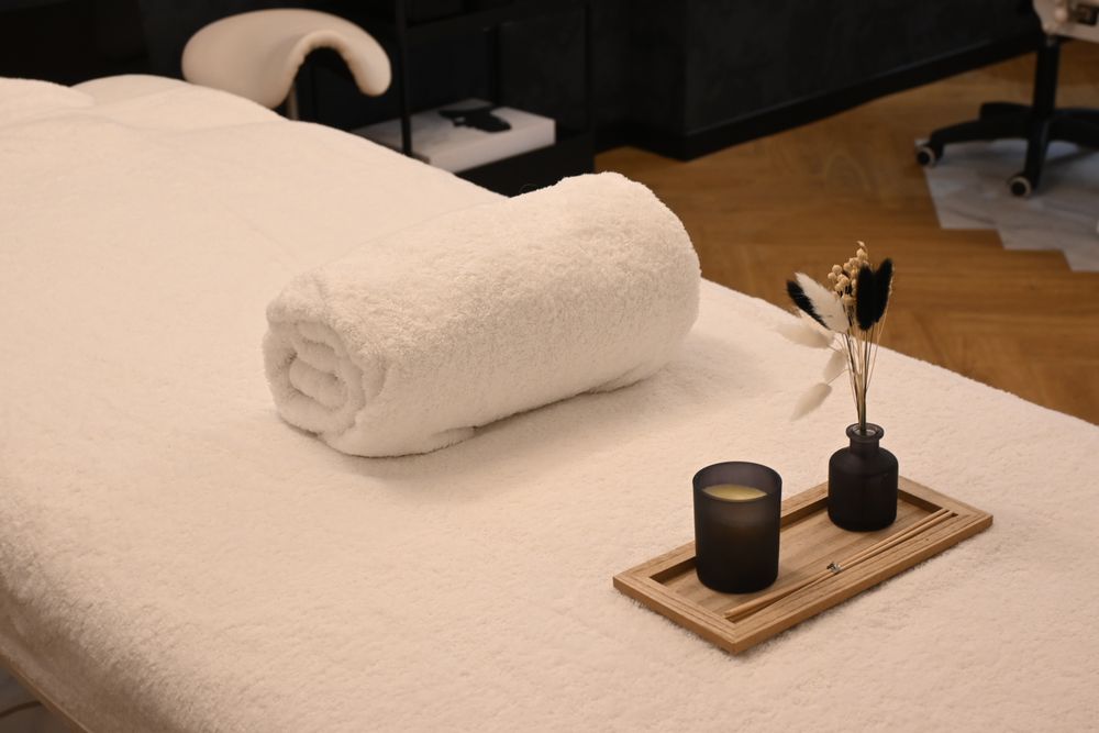 A treatment table made up with a towel and a candle