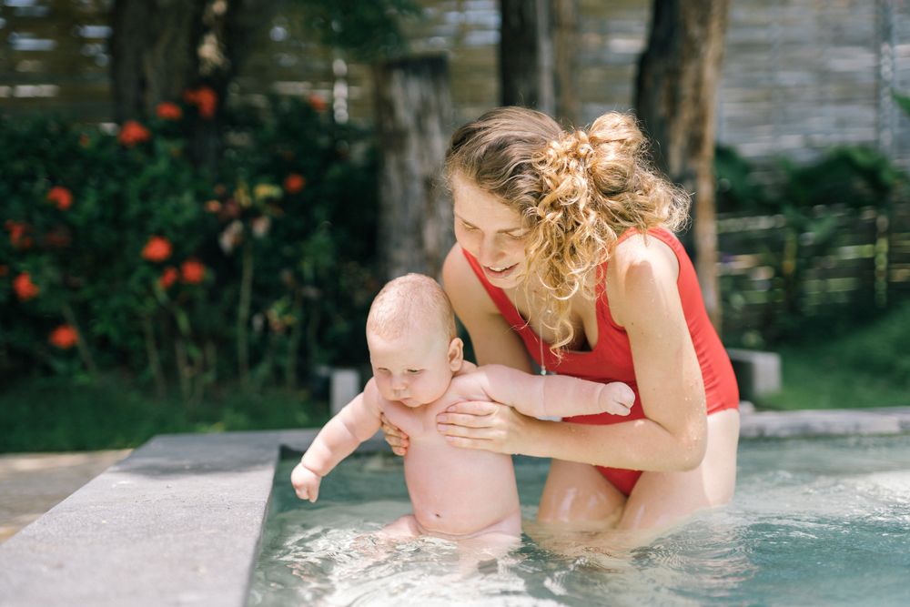 A parent holding a baby in the shallow end