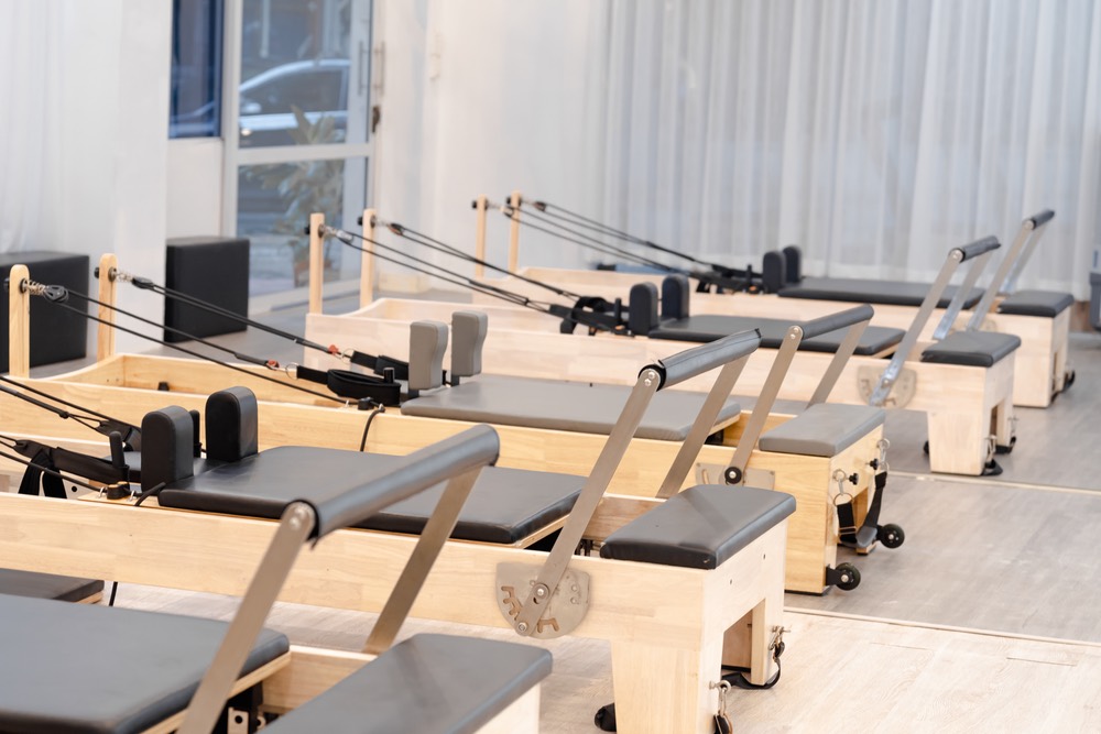 A row of pilates reformers in a bright studio