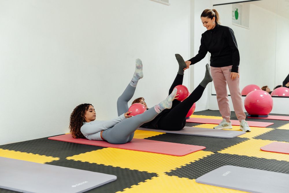A teacher guiding a pilates class on the mats