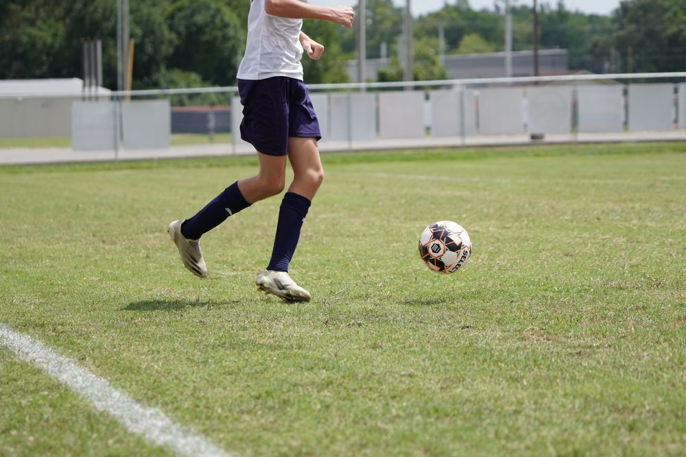 A young player kicking a soccer ball down the field